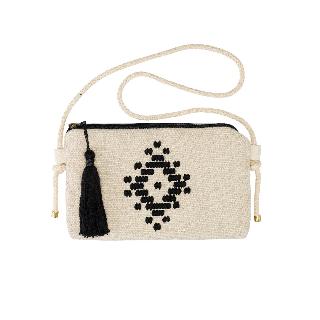 An off-white woven crossbody bag with a black geometric diamond pattern, a black tassel, and a cream-colored rope strap with gold-toned metal tips, shown against a plain white background.