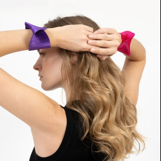 Woman using purple and pink hair clips on a white background