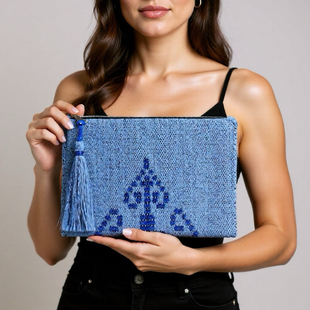 Woman holding a blue clutch with intricate design and tassel