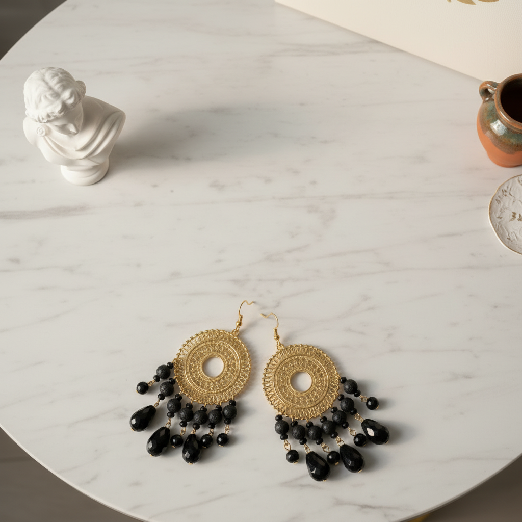 Gold earrings with black beads on a marble surface