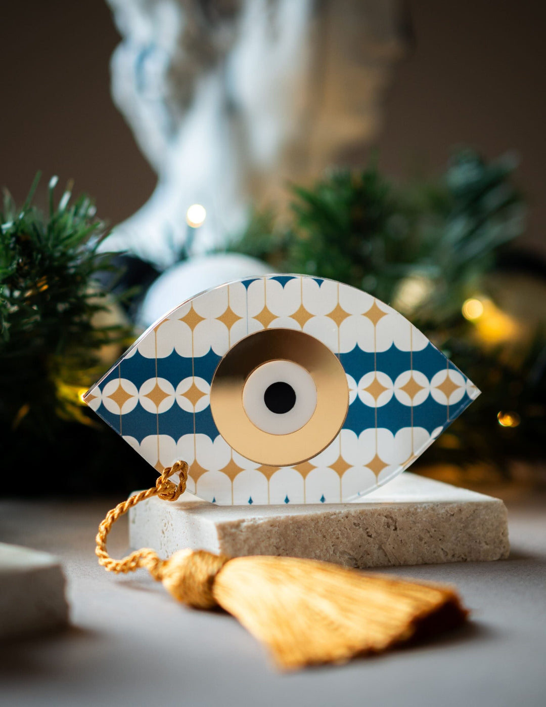 Decorative eye-shaped ornament with gold accents on a neutral background
