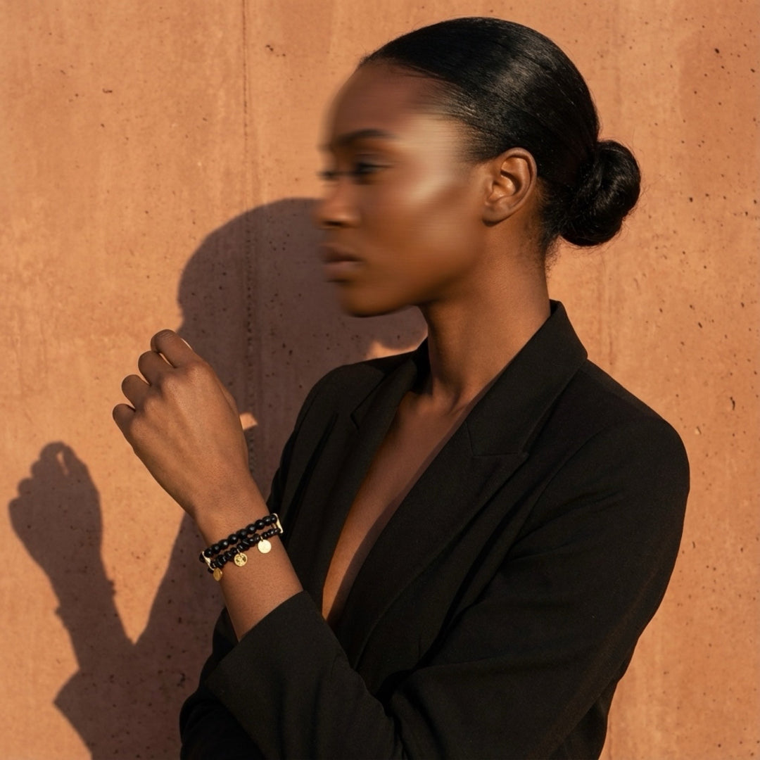 Woman wearing a black outfit and bracelets against an orange wall