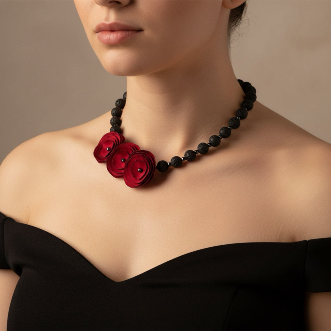 Necklace with red floral pendants and black beads worn by a person against a neutral background