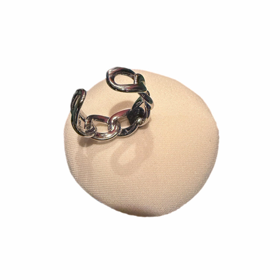 Silver chain ring on a beige fabric pad against a white background