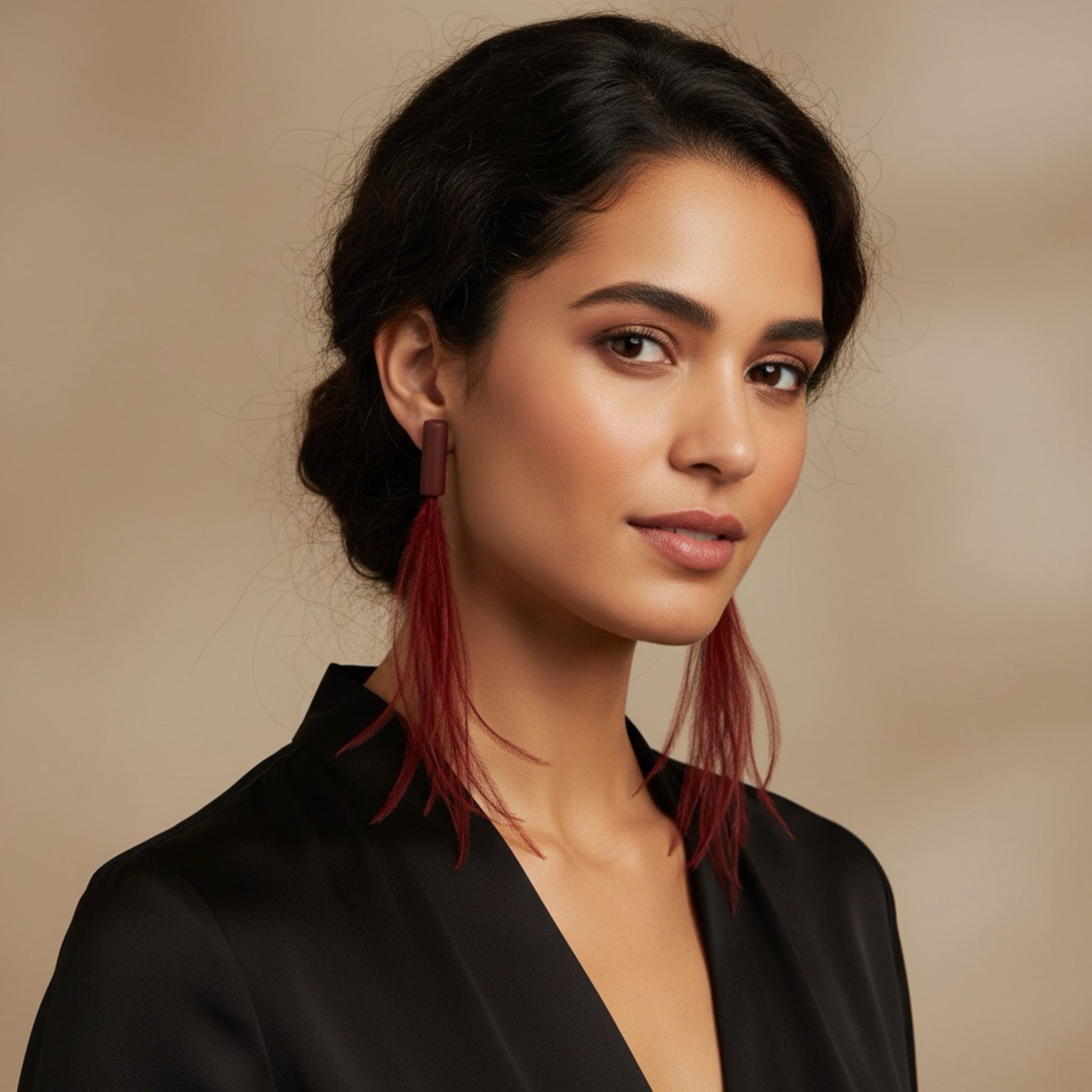 Woman wearing a black outfit with red earrings against a beige background
