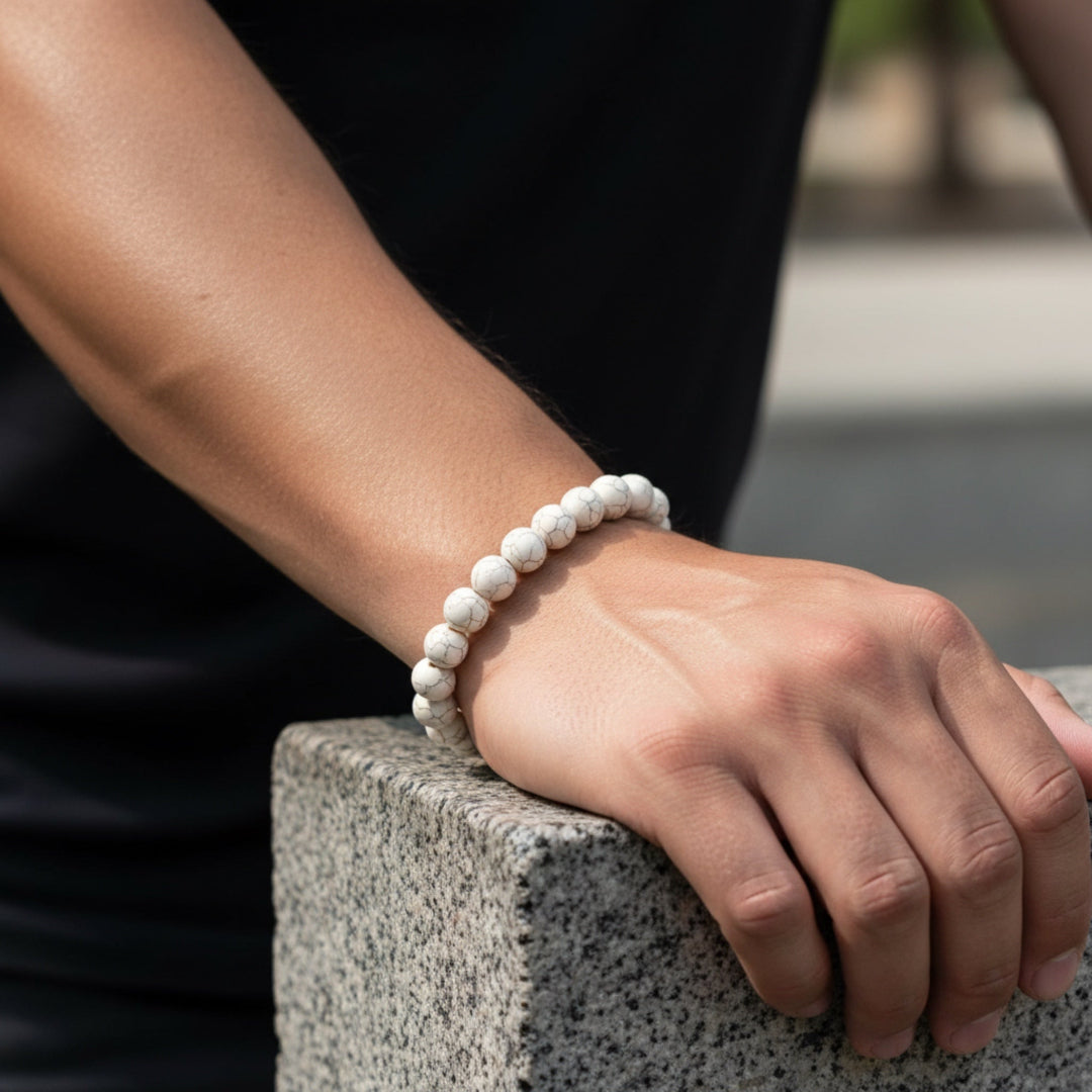 Person wearing a white beaded bracelet on a blurred outdoor background
