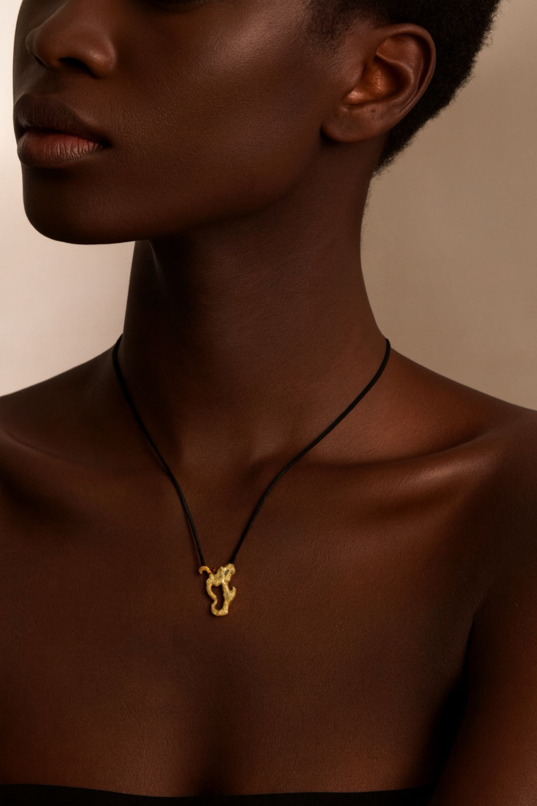 Close-up of a person wearing a gold necklace with a pendant on a neutral background