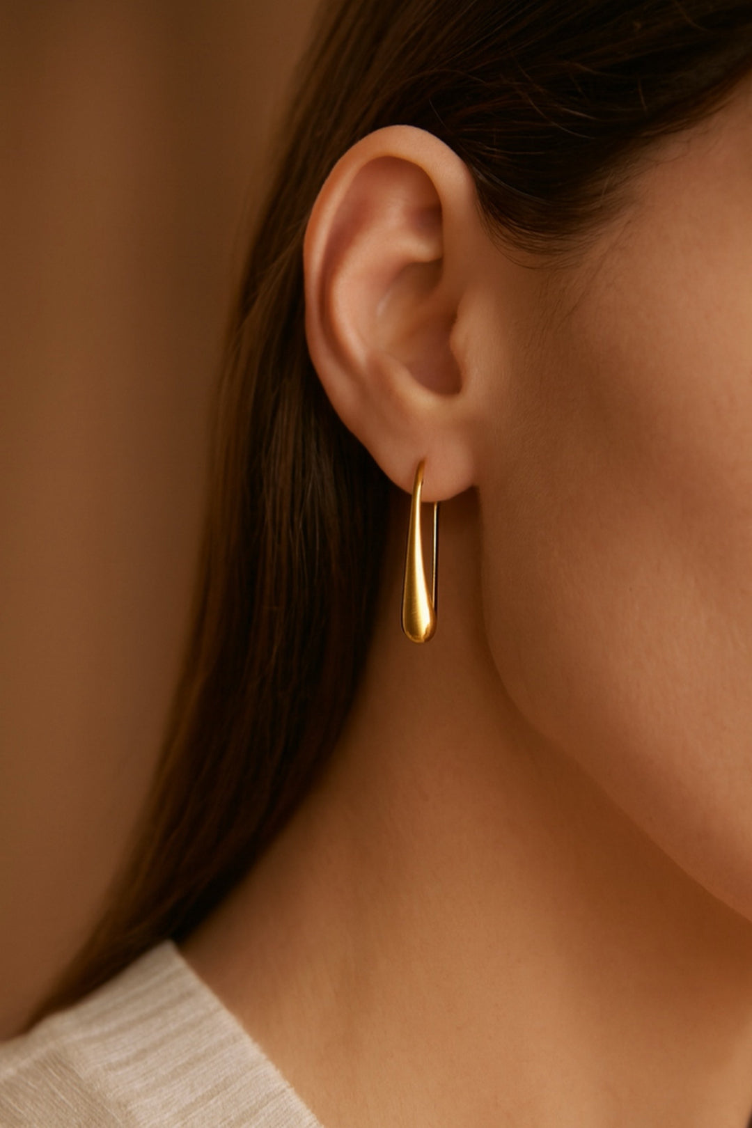 Gold hoop earring worn by a person with a blurred background