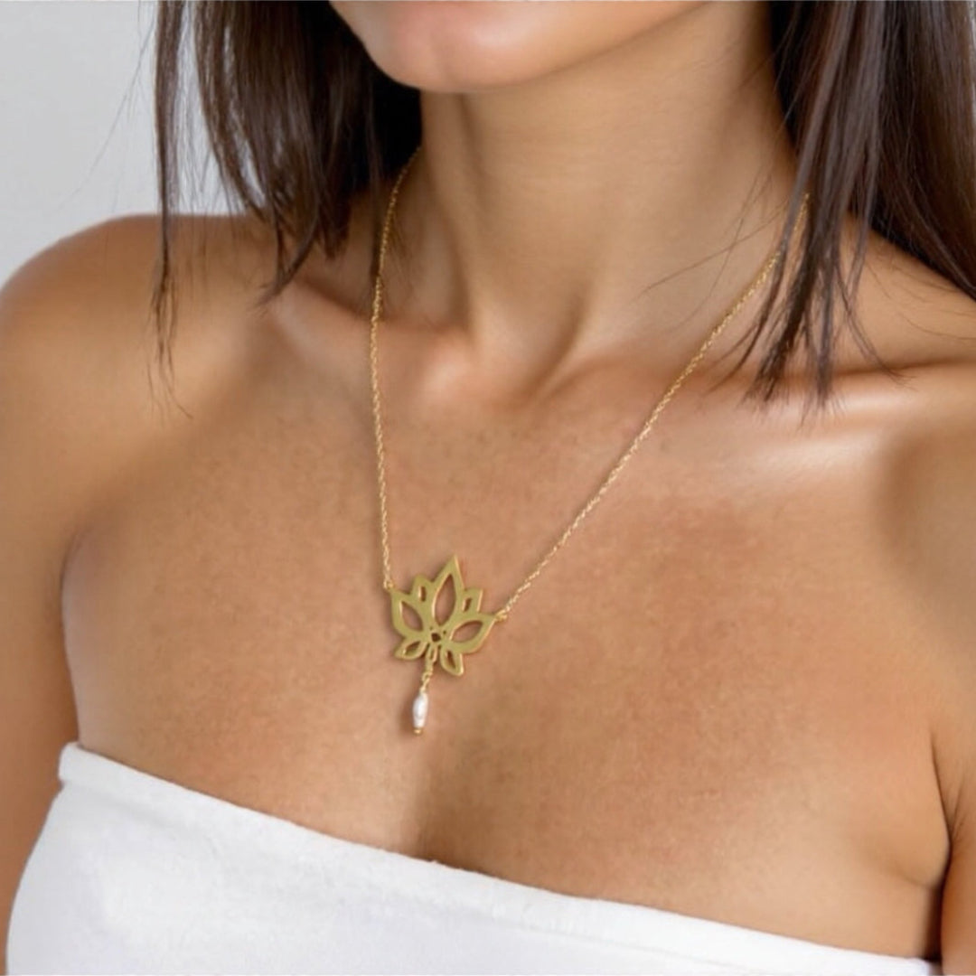 Gold necklace with a floral pendant worn by a person