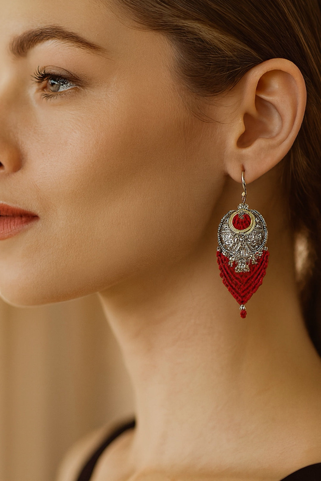 Close-up of a woman wearing a red and silver earring against a neutral background