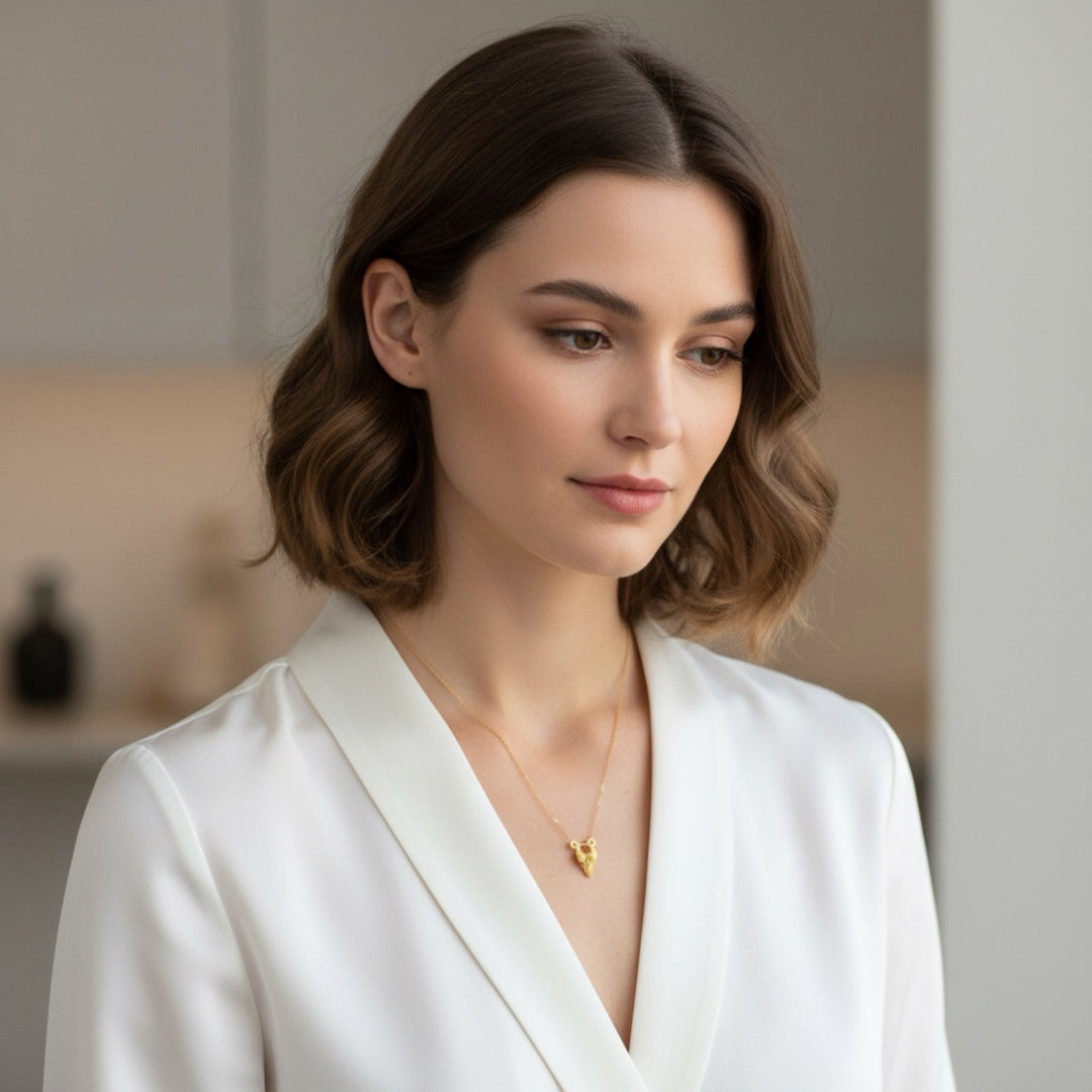 Woman wearing a white blazer and gold necklace in a neutral setting