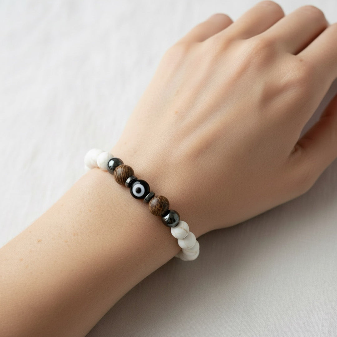 Hand wearing a bracelet with beads on a light background
