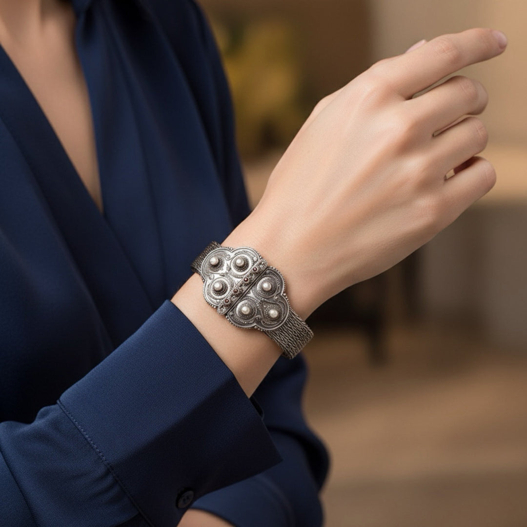 Close-up of a hand wearing an ornate silver bracelet on a blurred background