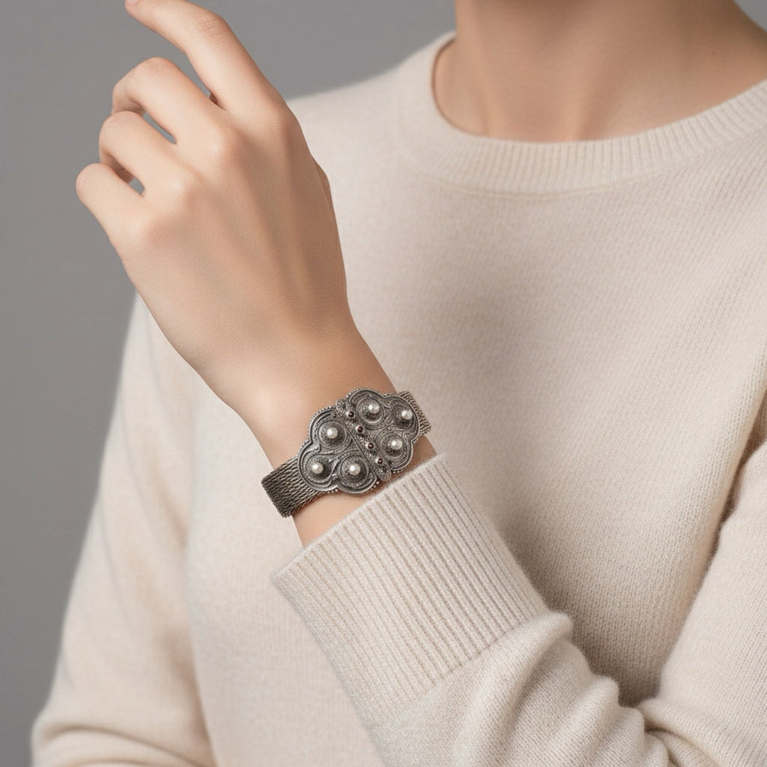 Silver bracelet on a person's wrist with a neutral background