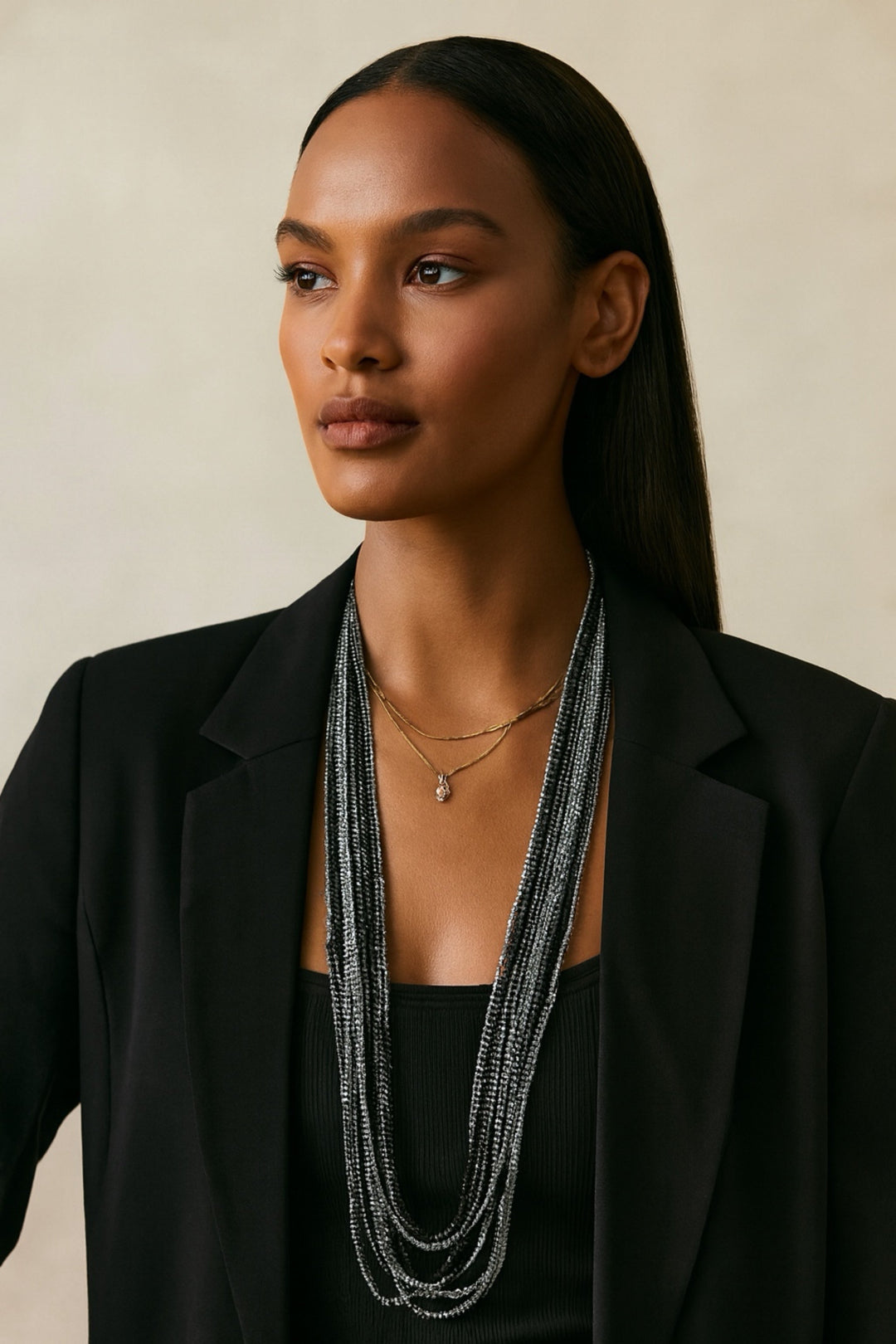 Woman wearing a long, layered necklace with a neutral background