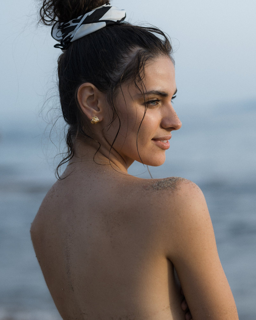 Woman with a headband looking over her shoulder at the ocean