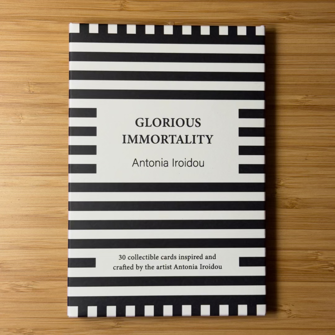 Book titled 'Glorious Immortality' by Antonia Iroidou with black and white striped cover on a wooden surface