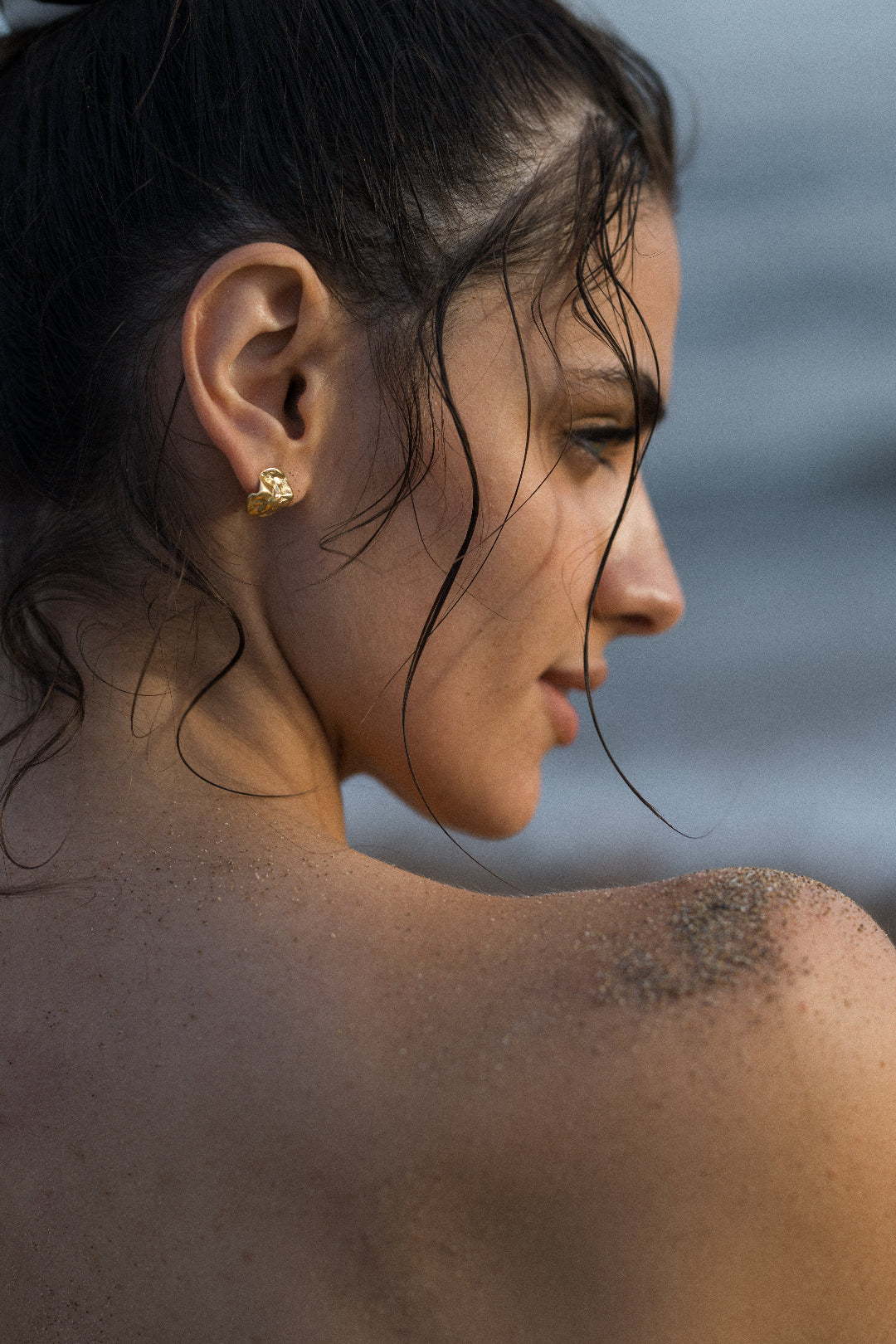 Close-up of a woman's profile with wet hair against a blurred natural background