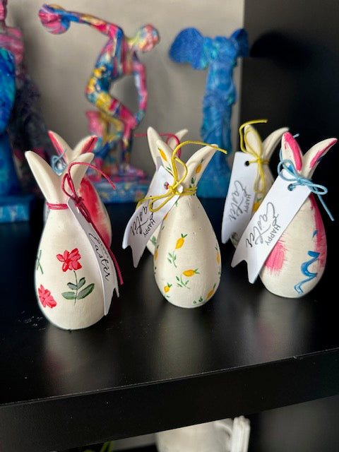 Decorative Easter bunnies with colorful handles on a dark surface
