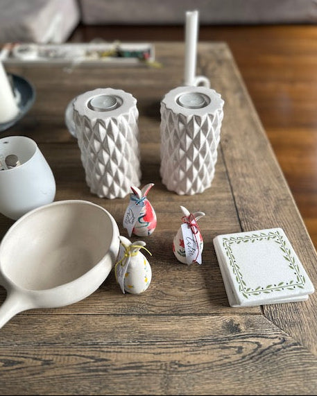 Decorative items on a wooden table including ceramic pots, a spoon, and small figurines.