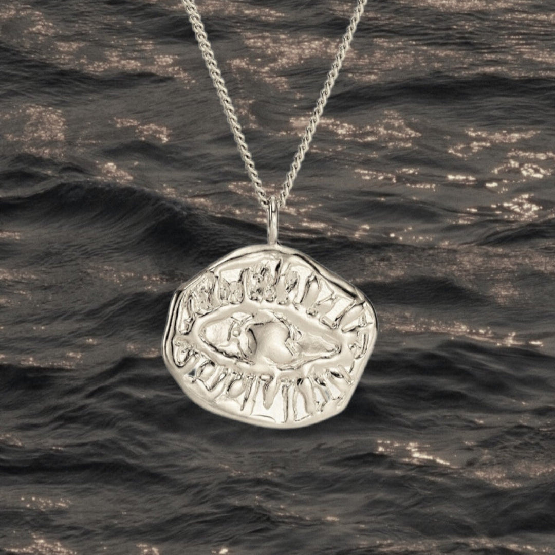 Silver necklace with a pendant over wavy water