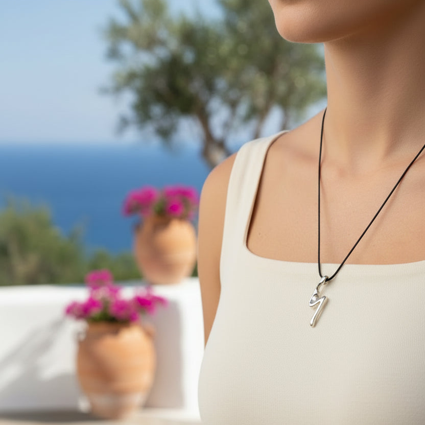 Person wearing a necklace with a heart pendant against a blurred outdoor background