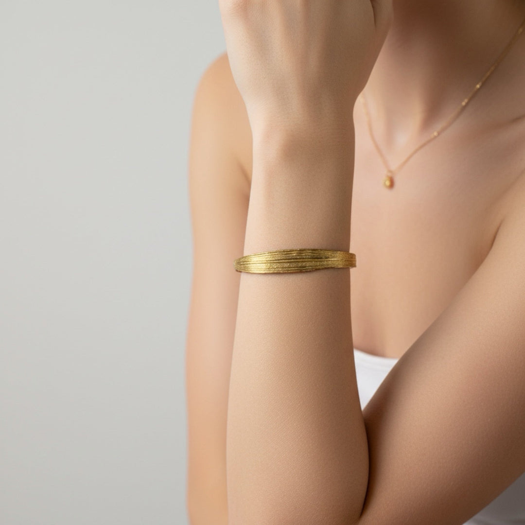 Gold bracelet on a person's wrist with a plain background