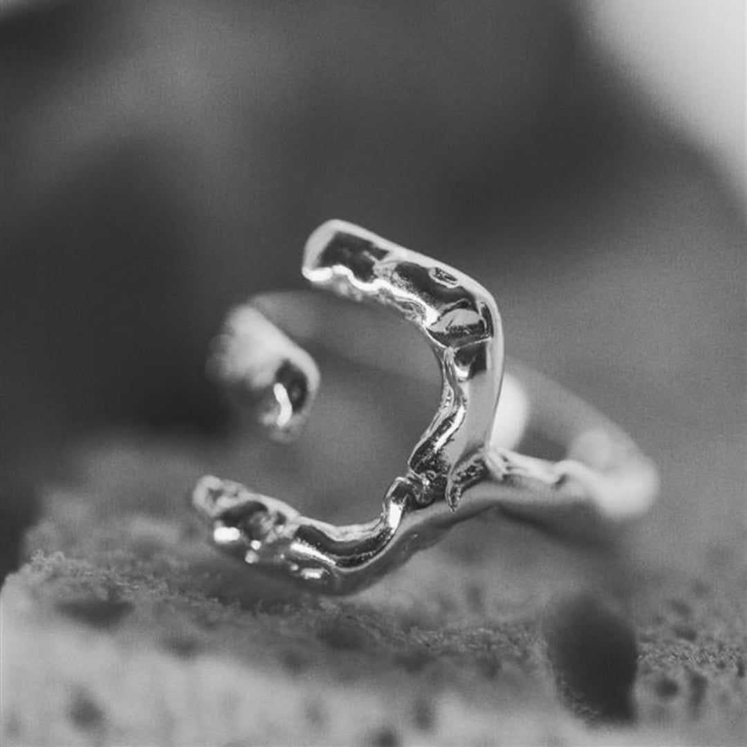 Silver ring with a unique design on a textured surface