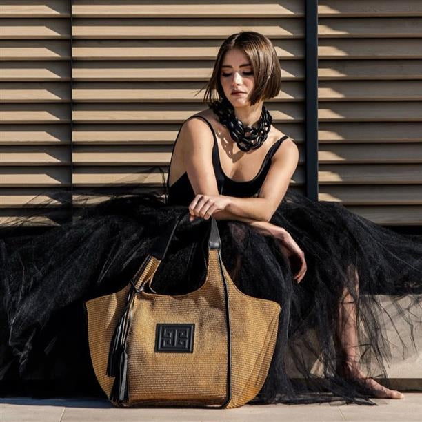 Woman holding a woven bag against a wooden slat background