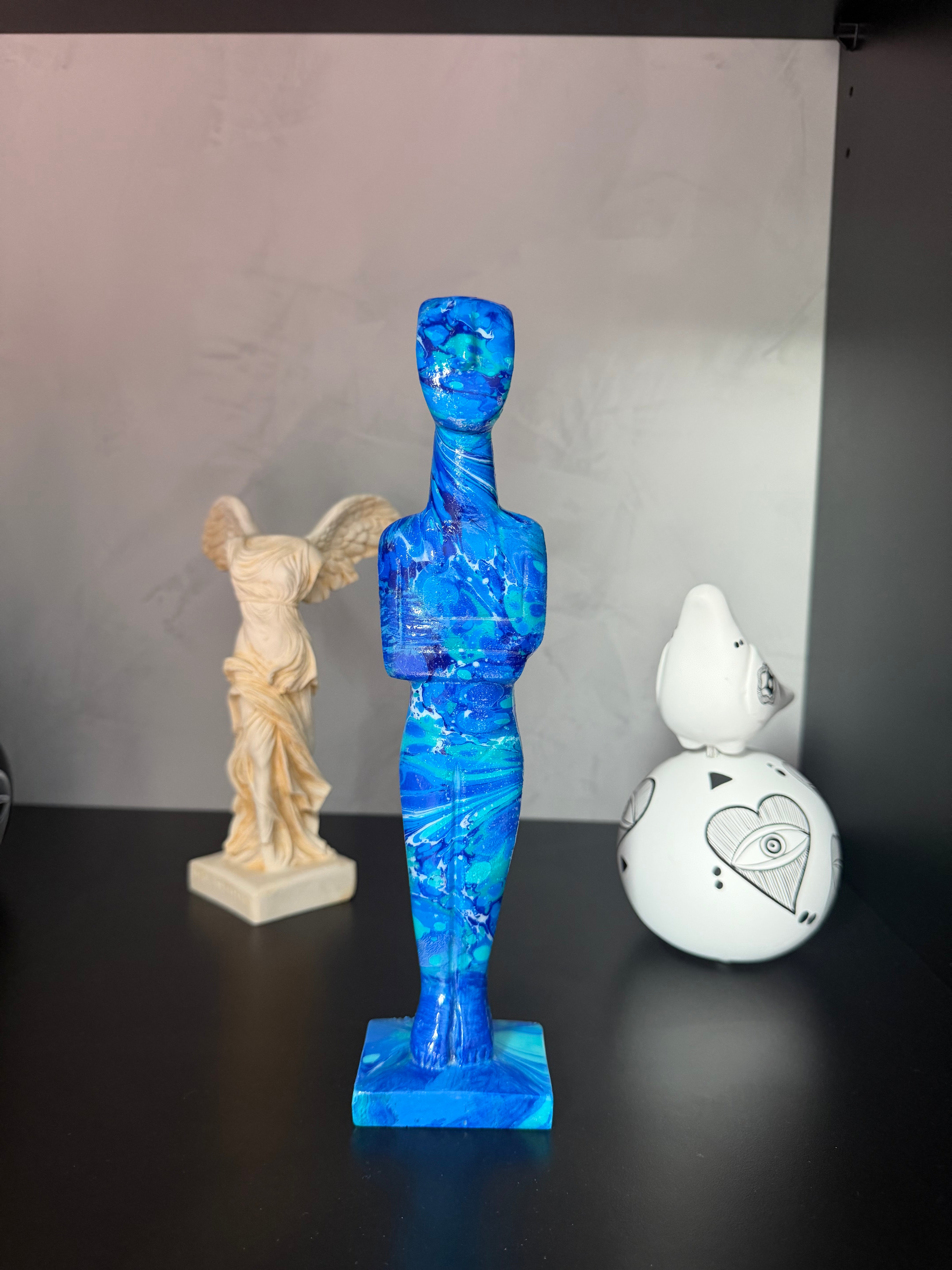 Blue and white decorative figure on a gray surface with a black background