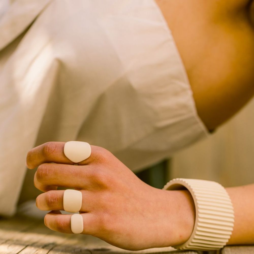 Close-up of a hand wearing two beige rings with a blurred background
