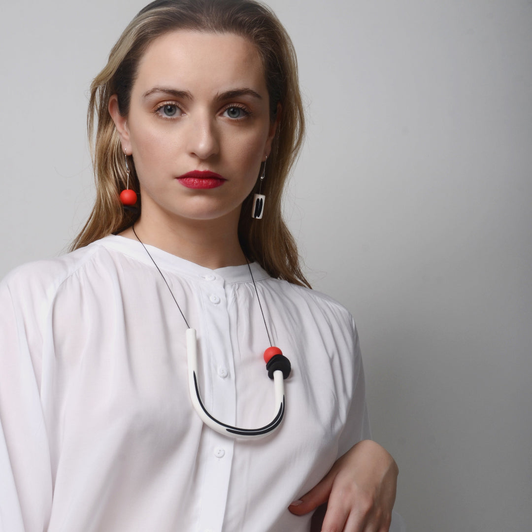 Woman wearing a white coat with a stethoscope around her neck against a plain background
