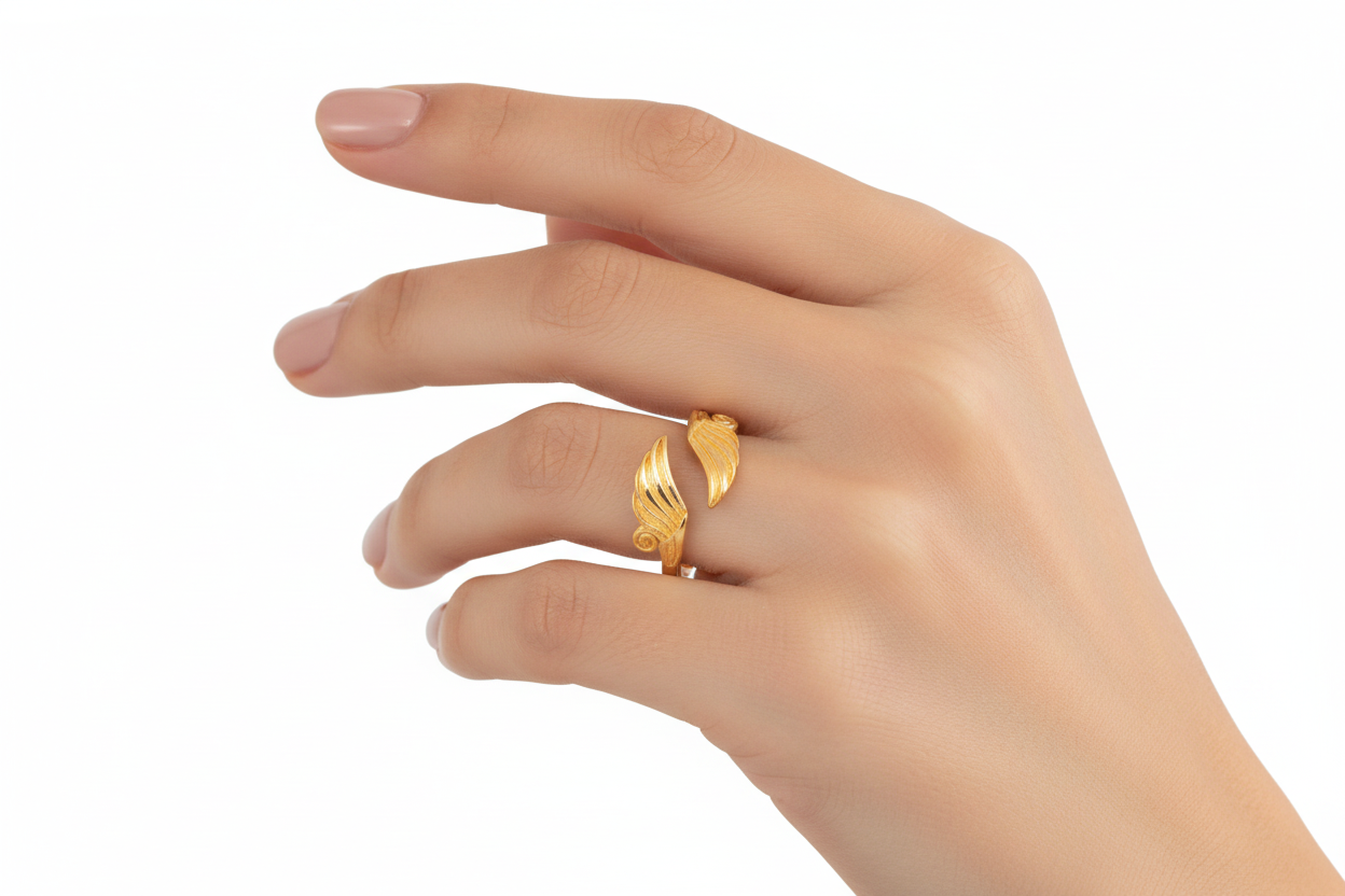 Gold wing-shaped ring on a hand against a white background