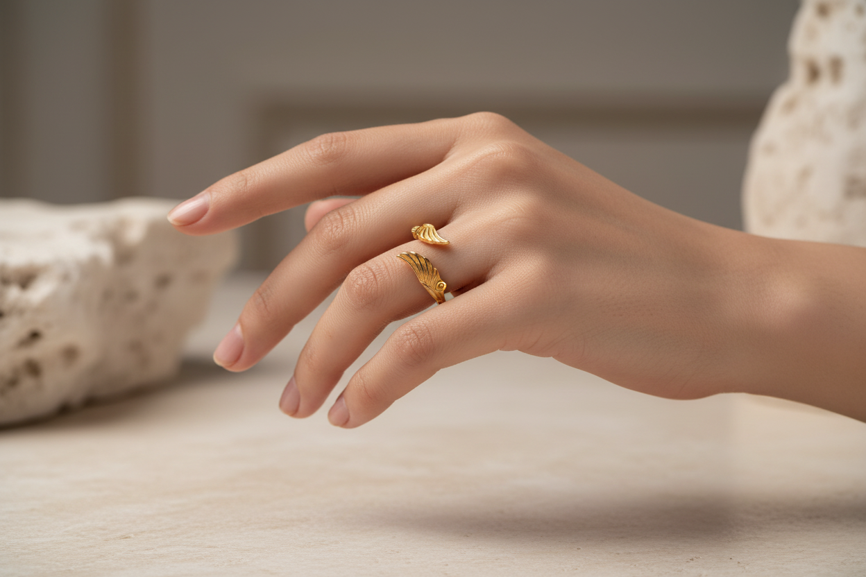 Hand wearing a gold ring with a neutral background