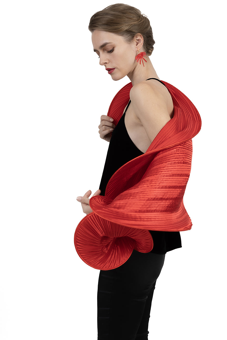 Woman wearing a red pleated garment over a black top on a white background