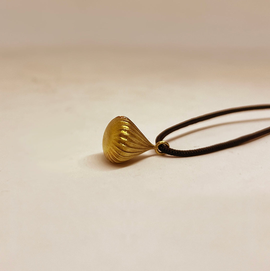 Gold necklace with a unique pendant on a beige background