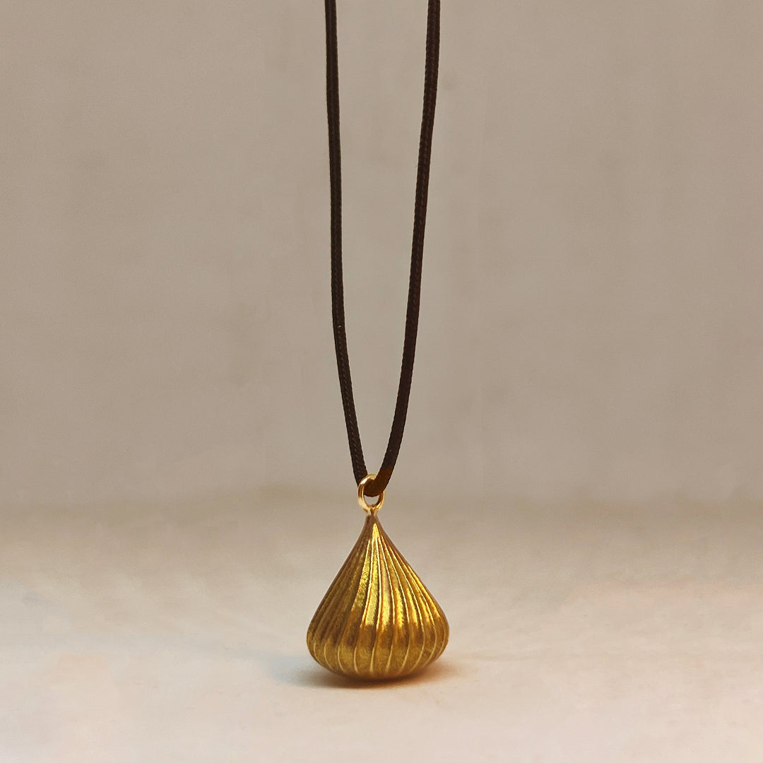 Gold pendant on a brown cord against a beige background