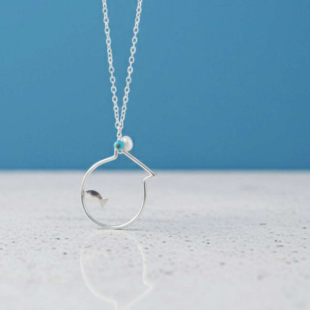 Silver necklace with a circular pendant on a blue and white background