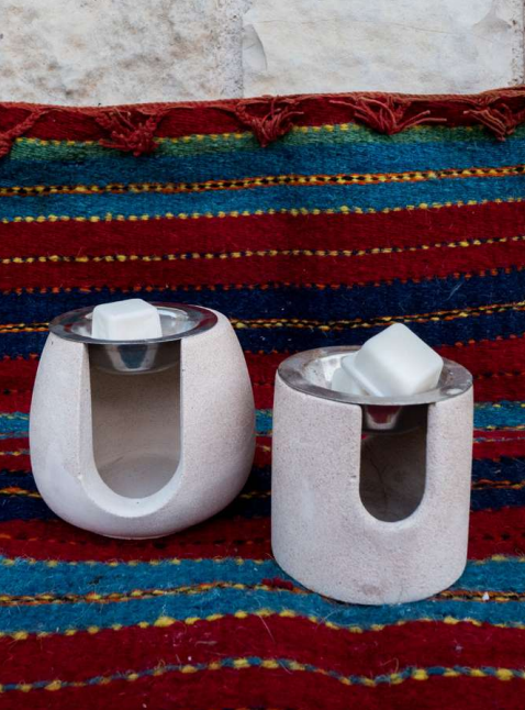 Two concrete candle holders with silver bases on a colorful striped fabric background