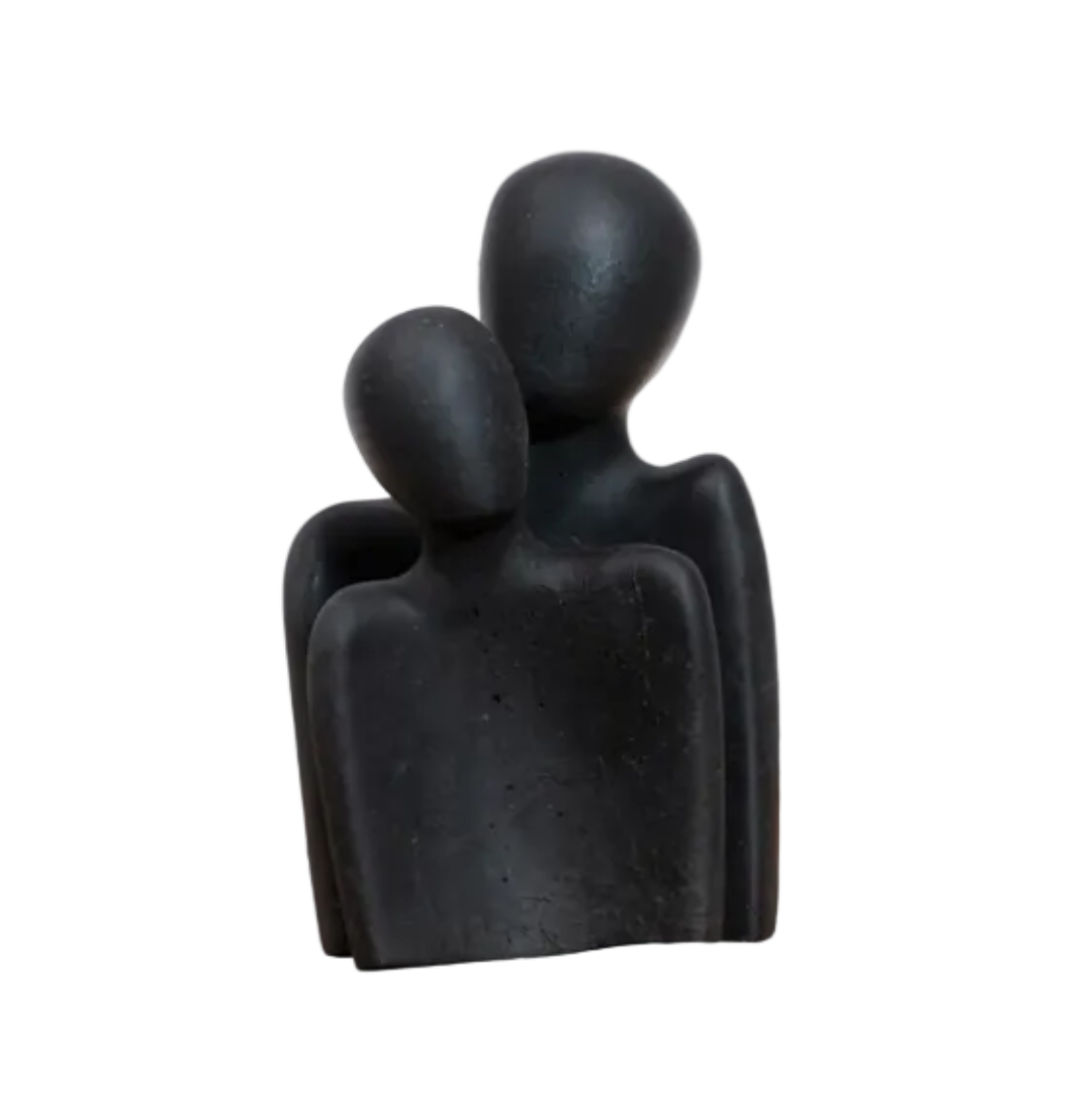 Black abstract sculpture of two figures embracing on a white background