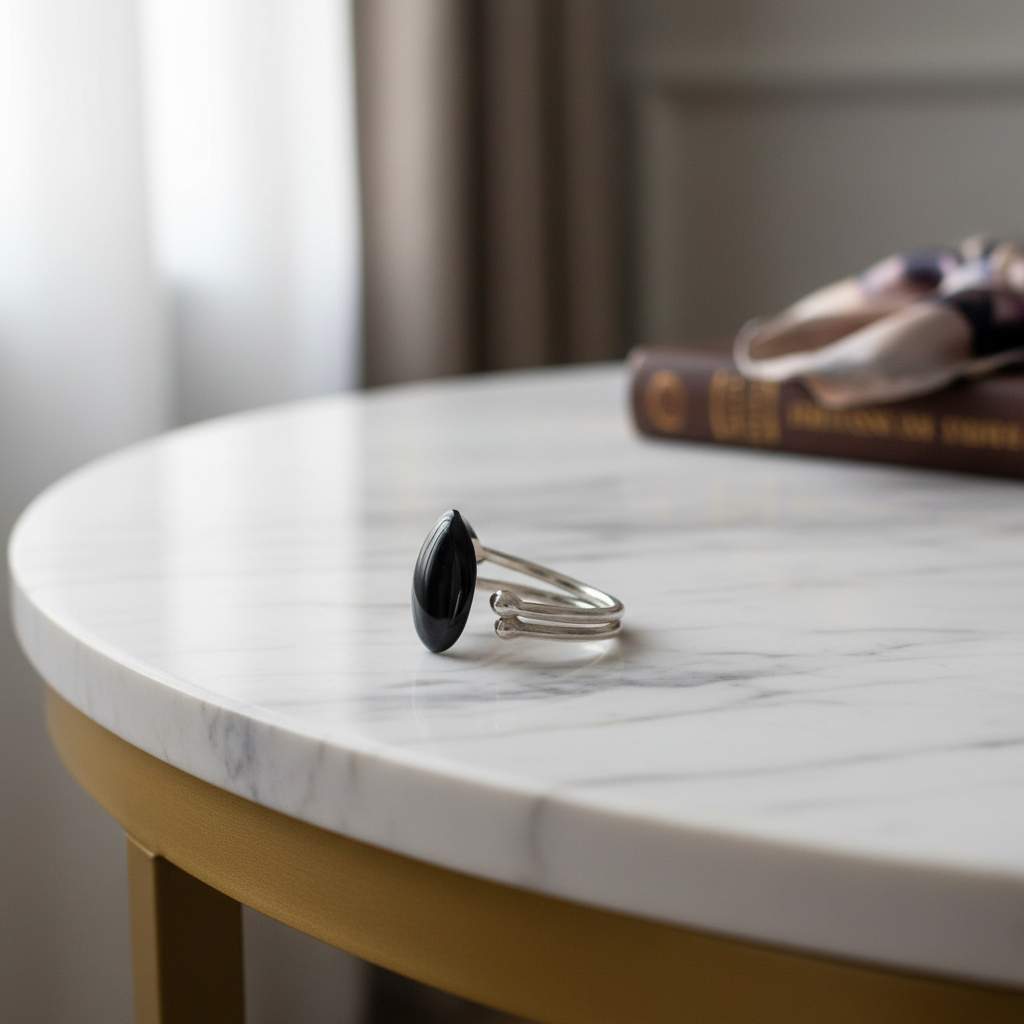 Silver ring with a black stone on a marble table