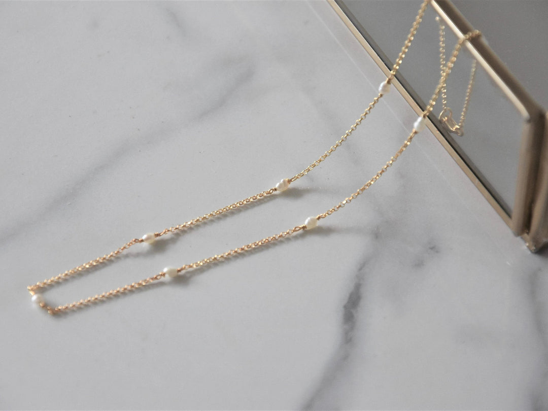 Gold necklace with small pearls on a marble surface