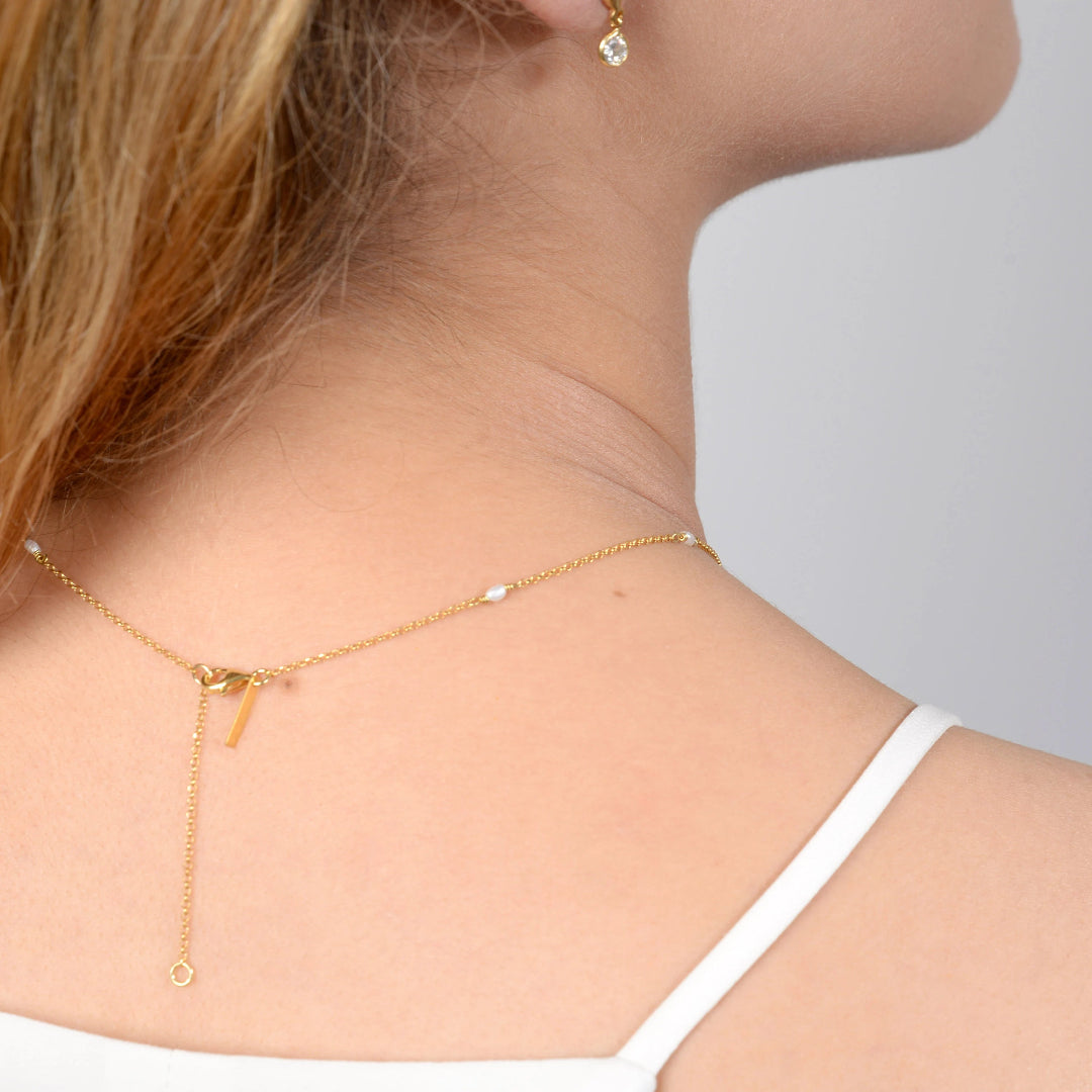 Gold necklace worn by a person with a neutral background