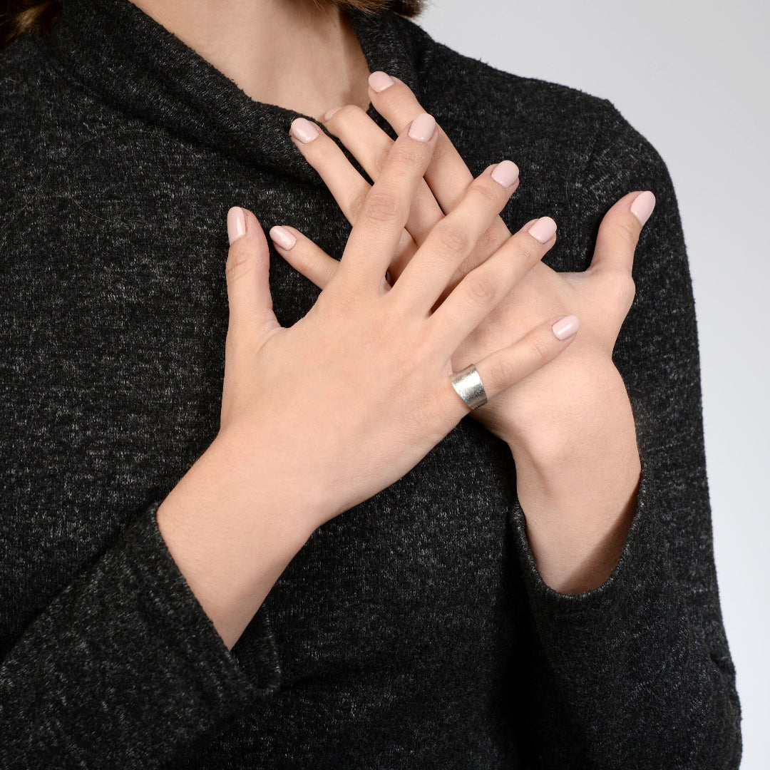 Close-up of a person wearing a dark gray sweater with hands clasped together.