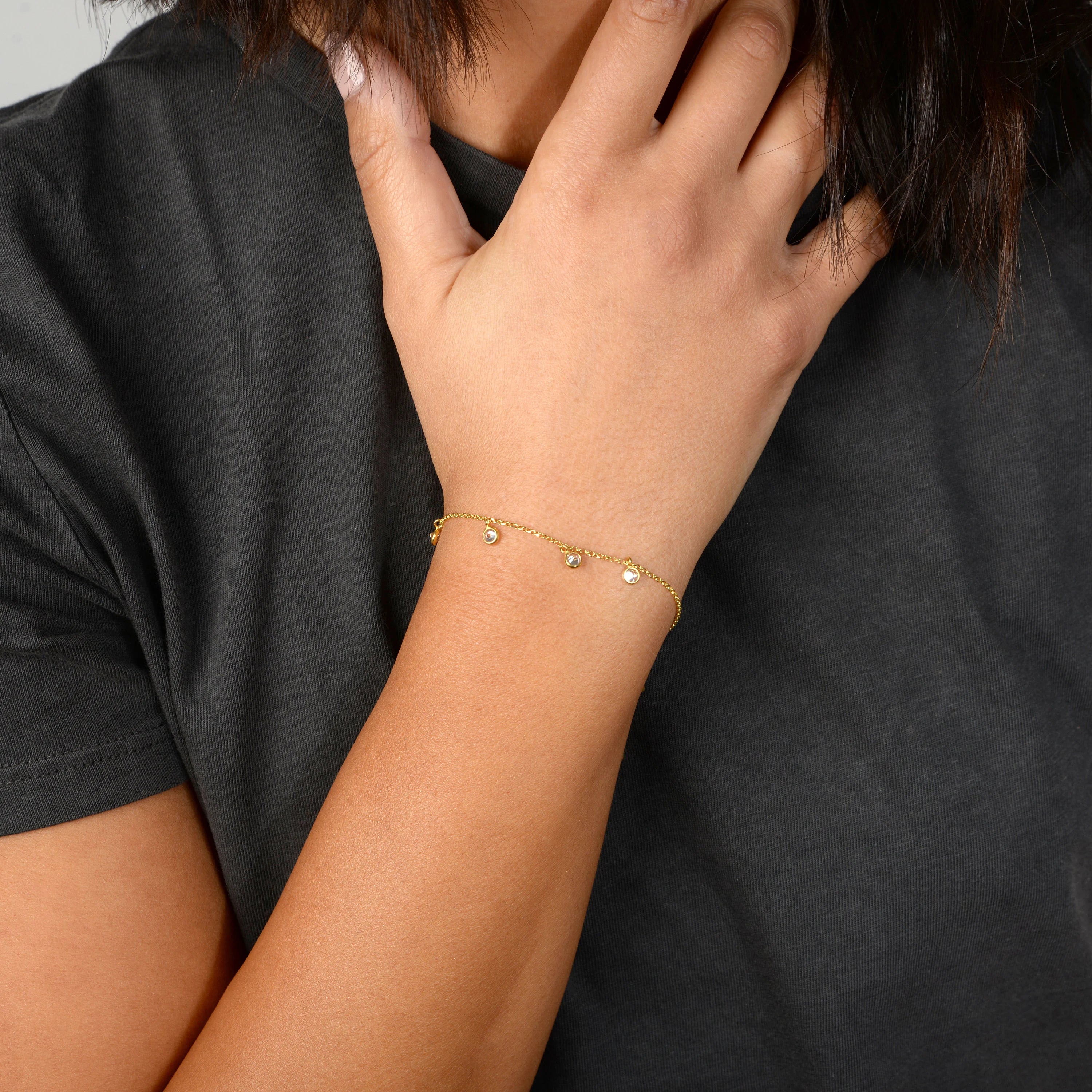 Gold bracelet on a wrist with a plain background