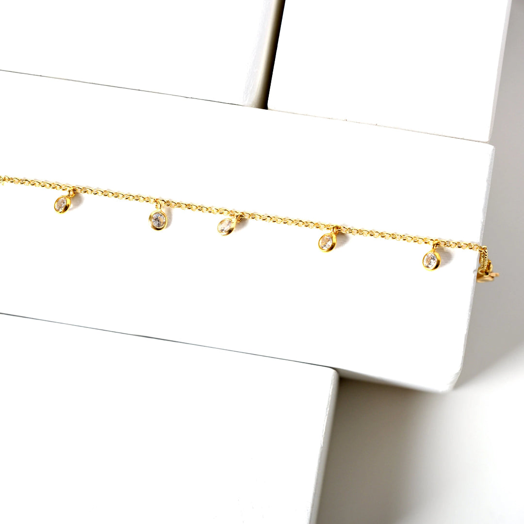 Gold bracelet with small round beads on a white surface