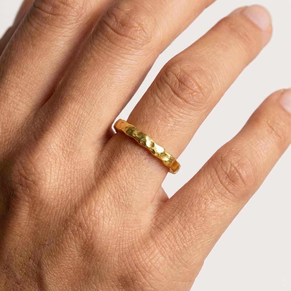 Gold ring on a person's finger against a white background