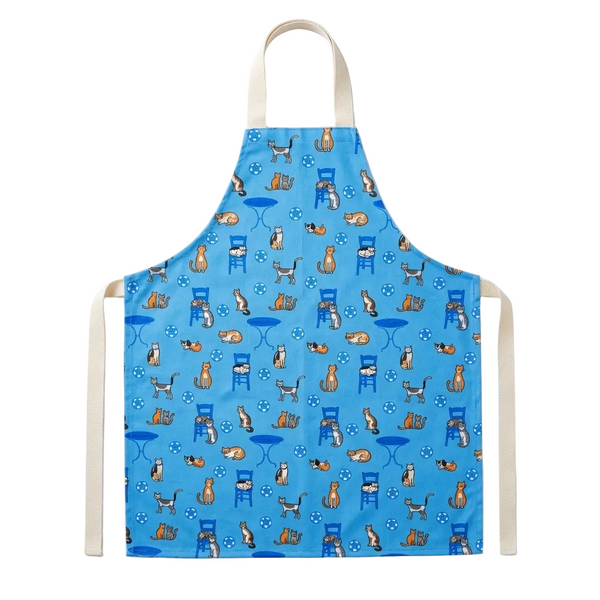 A light blue apron with a repeating pattern of orange tabby cats sitting on blue chairs and tables, featuring cream-colored neck and waist straps, shown against a plain white background.