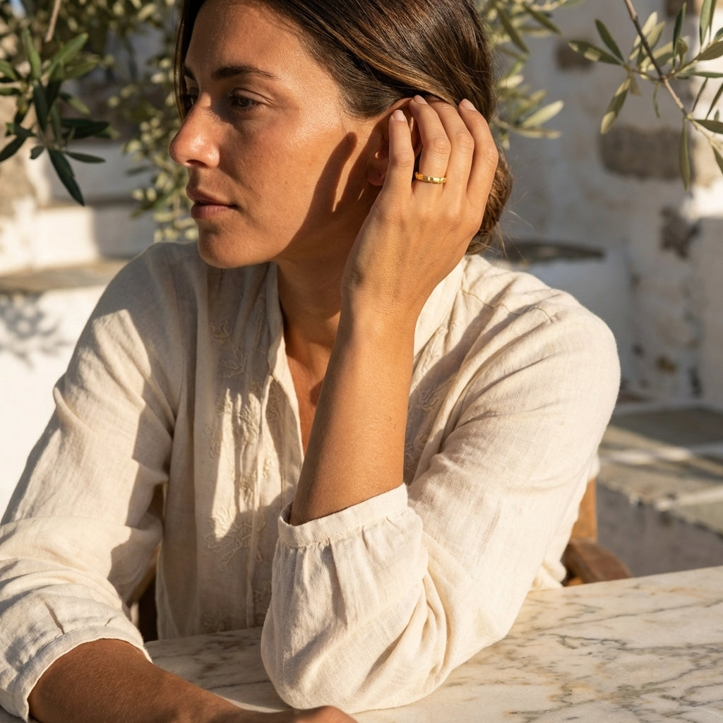 Woman in a white shirt sitting outdoors with plants in the background