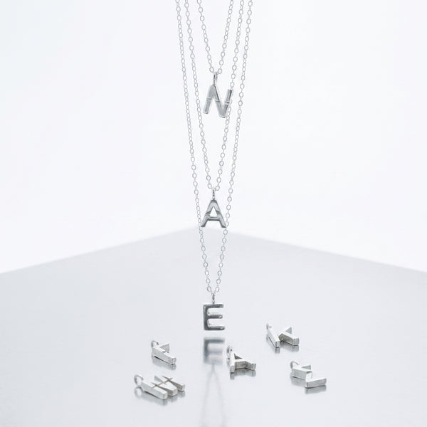 Silver necklace with letter pendants on a white background